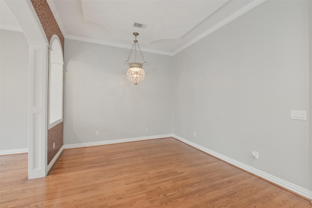 empty room featuring decorative columns, light hardwood / wood-style flooring, a notable chandelier, and ornamental molding