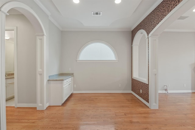 corridor with light hardwood / wood-style floors and ornamental molding