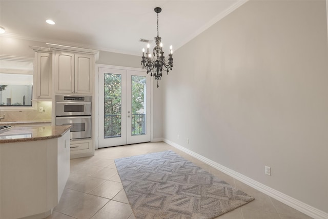 kitchen with light tile patterned flooring, ornamental molding, double oven, and french doors