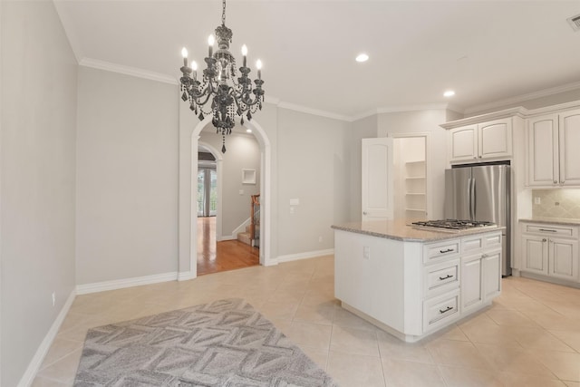 kitchen with tasteful backsplash, white cabinetry, stainless steel appliances, and crown molding