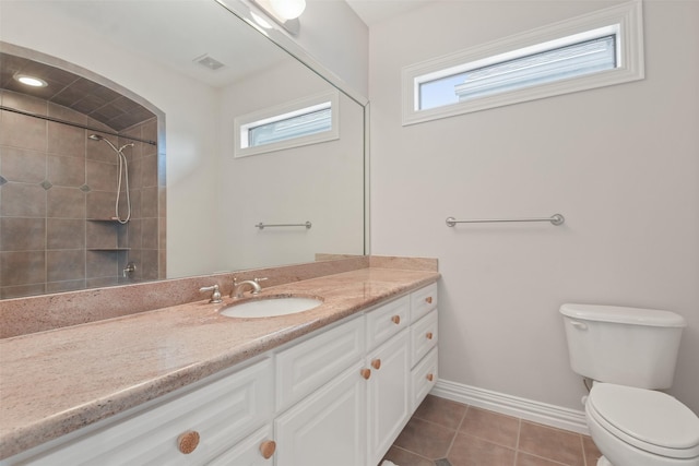 bathroom with tiled shower, tile patterned flooring, vanity, and toilet