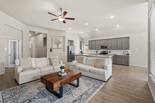 living room with light hardwood / wood-style flooring, ceiling fan, lofted ceiling, and sink