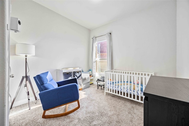 carpeted bedroom featuring a crib and vaulted ceiling