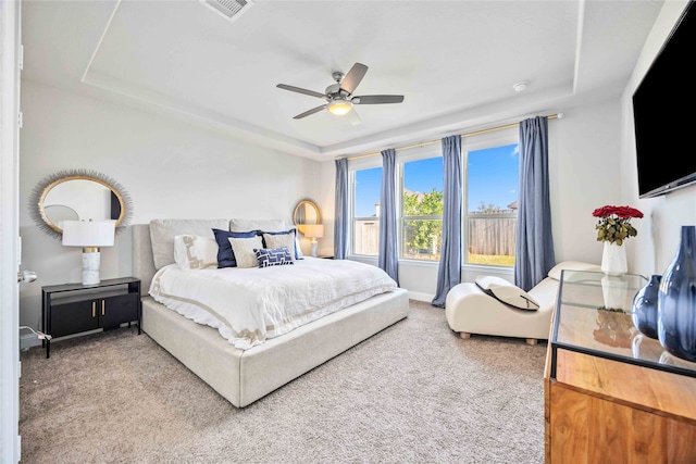 carpeted bedroom with ceiling fan and a tray ceiling