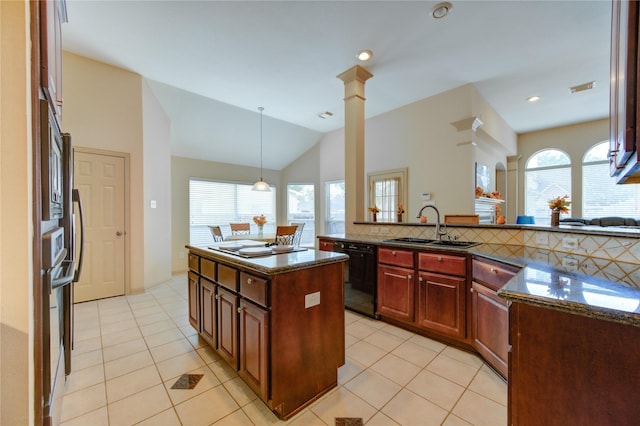 kitchen with decorative light fixtures, dark stone counters, dishwasher, and a sink