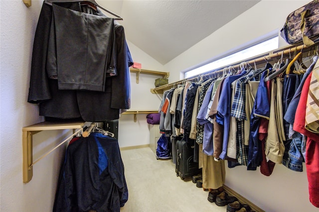 walk in closet with light colored carpet and lofted ceiling