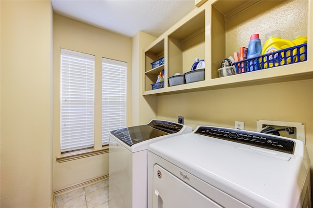 laundry area featuring washing machine and dryer, light tile patterned floors, and a textured ceiling