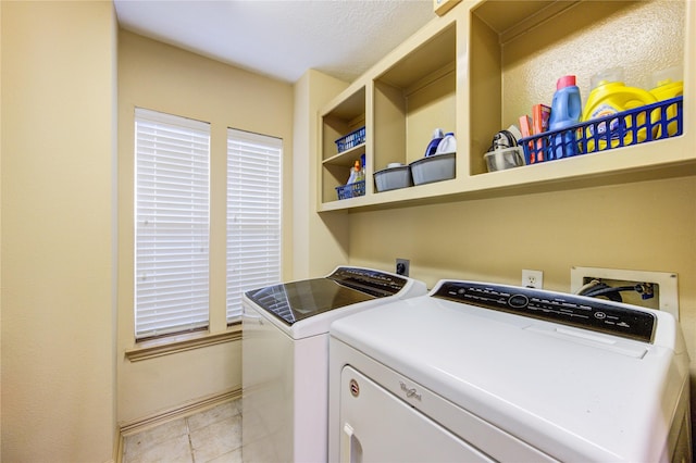 washroom with washing machine and dryer, light tile patterned flooring, laundry area, baseboards, and a textured ceiling