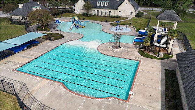 view of pool with a water slide, fence, and a yard