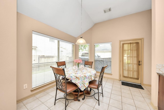 dining space with light tile patterned floors, visible vents, lofted ceiling, and baseboards