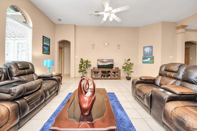 living area featuring light tile patterned floors, ceiling fan, and arched walkways