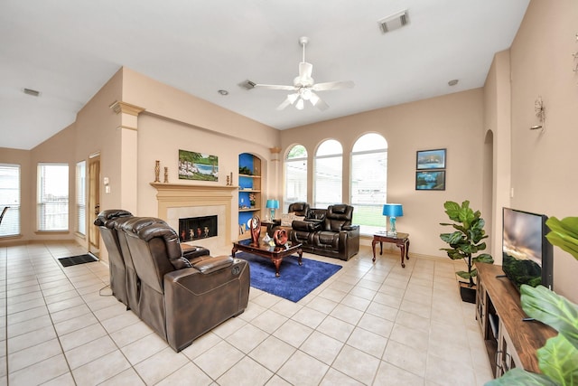 living room featuring a tiled fireplace, visible vents, light tile patterned floors, and a ceiling fan