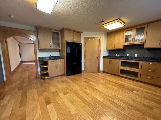 kitchen with black refrigerator, light wood-type flooring, and a textured ceiling