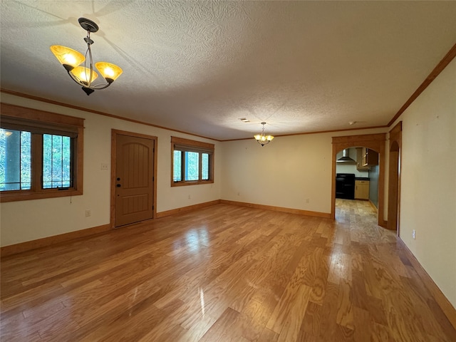 unfurnished living room with plenty of natural light, light hardwood / wood-style floors, a textured ceiling, and an inviting chandelier