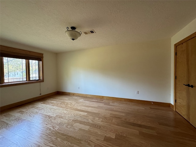 empty room featuring a textured ceiling and light hardwood / wood-style floors