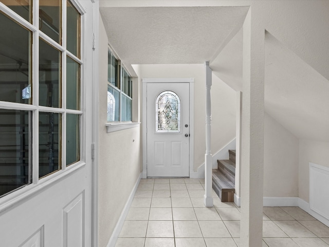 tiled entryway with a textured ceiling and vaulted ceiling