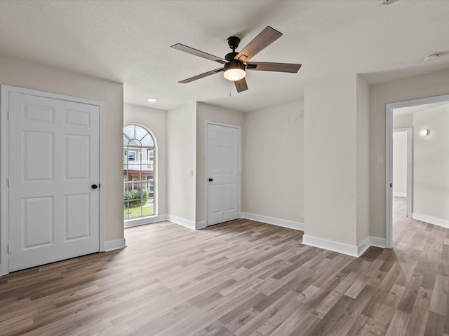 empty room featuring ceiling fan, light hardwood / wood-style floors, and a textured ceiling