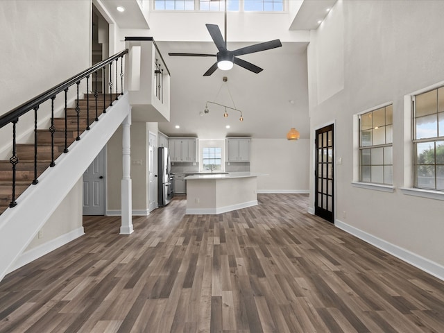 unfurnished living room featuring dark hardwood / wood-style floors, a healthy amount of sunlight, and a high ceiling