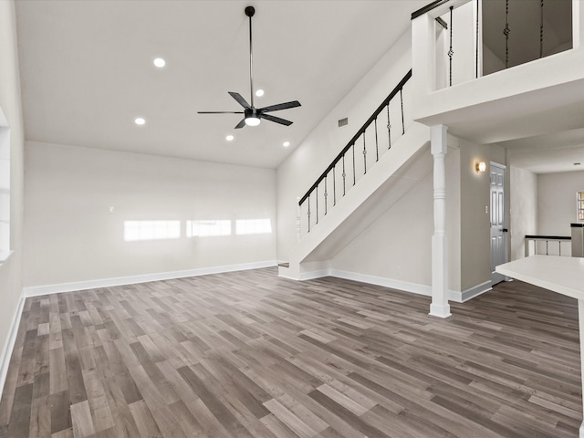 unfurnished living room featuring ceiling fan, wood-type flooring, and a high ceiling