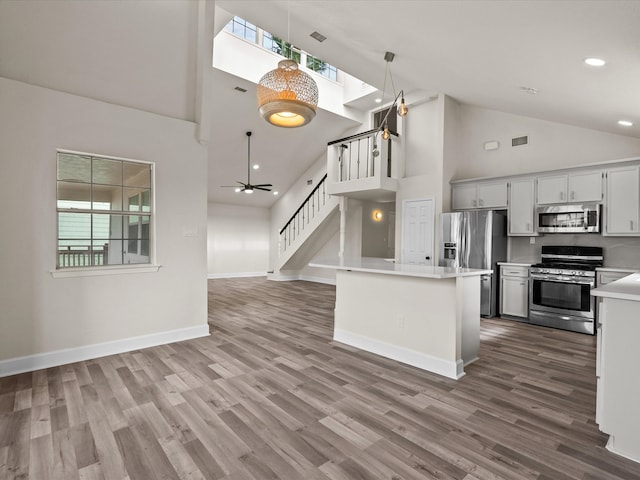 kitchen featuring high vaulted ceiling, dark hardwood / wood-style floors, ceiling fan, decorative light fixtures, and stainless steel appliances