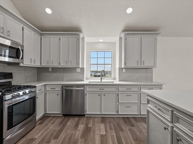 kitchen featuring white cabinets, backsplash, stainless steel appliances, and dark wood-type flooring