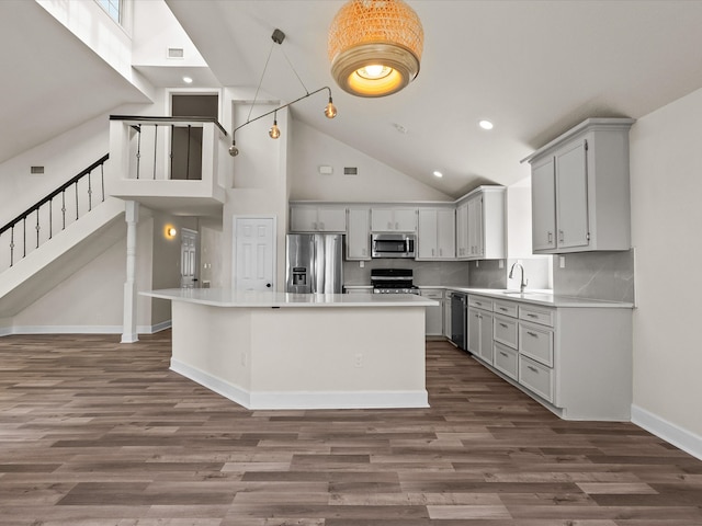 kitchen with dark hardwood / wood-style flooring, a kitchen island, high vaulted ceiling, and appliances with stainless steel finishes