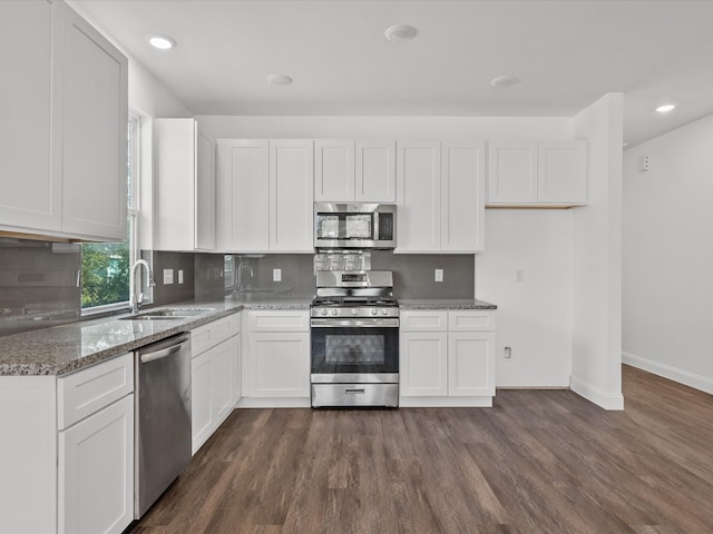 kitchen featuring stainless steel appliances, sink, stone counters, white cabinets, and dark hardwood / wood-style floors