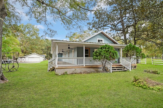 view of front facade with an outdoor structure, ceiling fan, covered porch, and a front yard