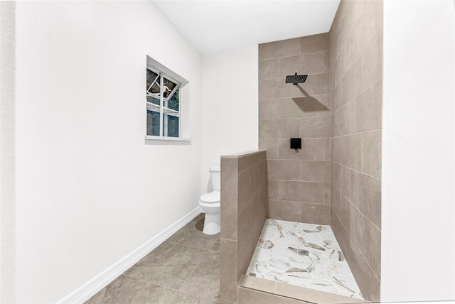 bathroom featuring tile patterned floors, toilet, and tiled shower