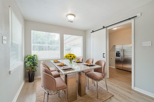 dining area with light wood-type flooring and a barn door