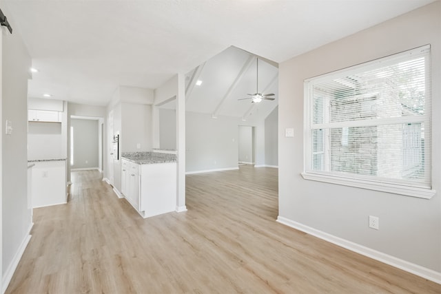 kitchen with light stone countertops, light wood-type flooring, ceiling fan, white cabinets, and vaulted ceiling with beams