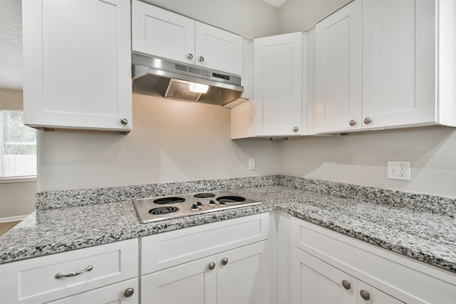 kitchen featuring white cabinets, light stone counters, and white electric stovetop