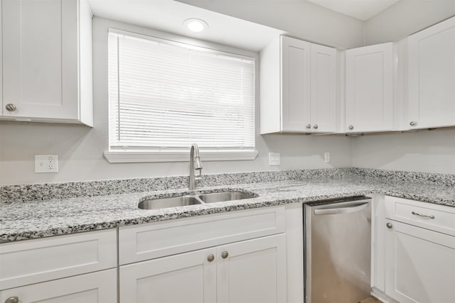 kitchen with light stone counters, white cabinetry, stainless steel dishwasher, and sink