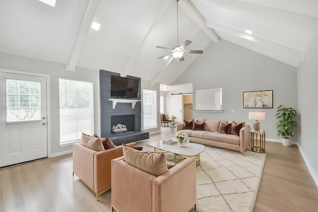 living room featuring beam ceiling, light wood-type flooring, high vaulted ceiling, and a barn door