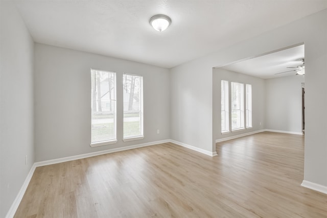 empty room featuring ceiling fan, plenty of natural light, and light wood-type flooring