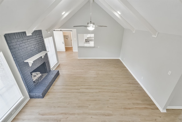 bonus room featuring lofted ceiling with beams, light hardwood / wood-style floors, ceiling fan, and a brick fireplace