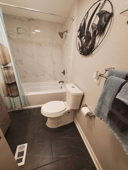 bathroom featuring toilet and shower / tub combo with curtain