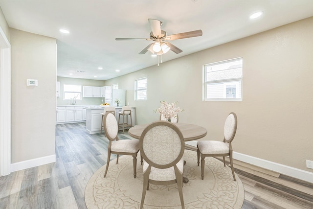 dining area with light hardwood / wood-style floors, ceiling fan, and sink