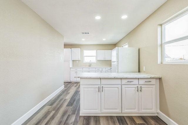 kitchen featuring white cabinets, light stone counters, white fridge, and dark hardwood / wood-style floors