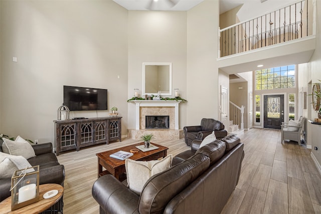 living room with a fireplace, a towering ceiling, and light hardwood / wood-style flooring