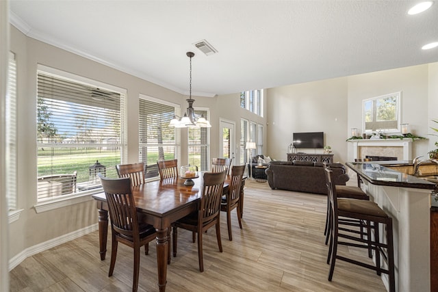 dining space featuring a textured ceiling, crown molding, plenty of natural light, and a notable chandelier