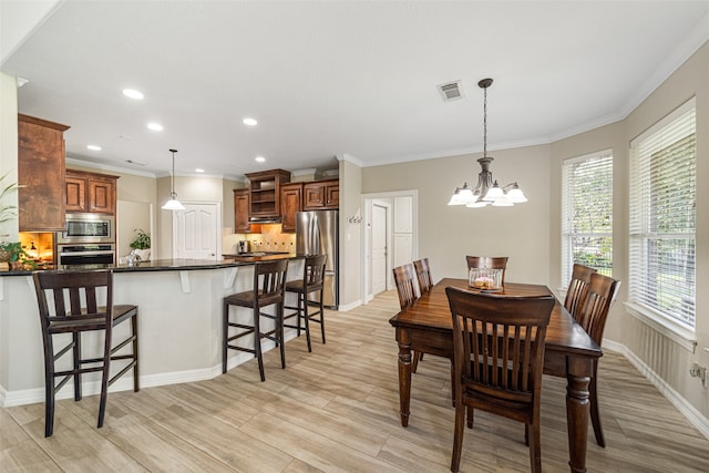 dining space featuring light hardwood / wood-style flooring, ornamental molding, and an inviting chandelier