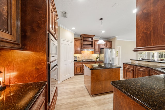 kitchen featuring appliances with stainless steel finishes, a kitchen island, ornamental molding, and dark stone counters