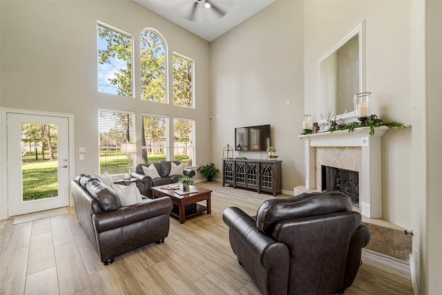 living room featuring ceiling fan, a towering ceiling, plenty of natural light, and a premium fireplace