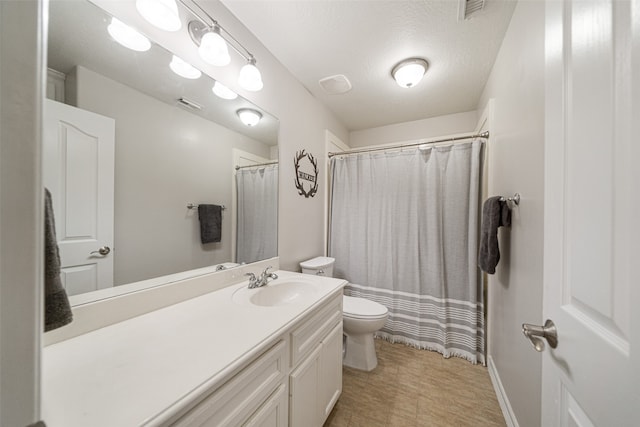 bathroom with a shower with shower curtain, vanity, toilet, and a textured ceiling