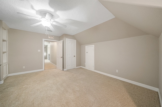 additional living space featuring ceiling fan, light colored carpet, a textured ceiling, and vaulted ceiling