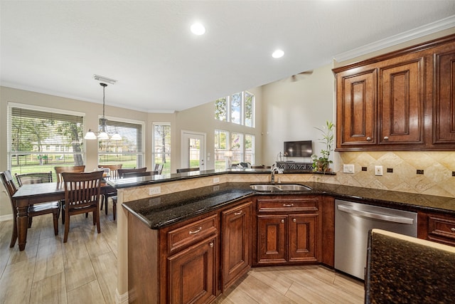 kitchen featuring kitchen peninsula, stainless steel dishwasher, sink, pendant lighting, and dark stone countertops