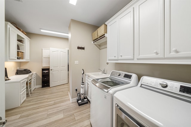 laundry area with light hardwood / wood-style floors, sink, cabinets, and independent washer and dryer