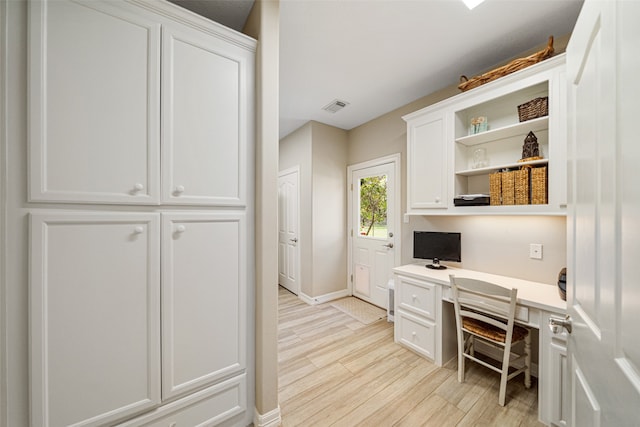 home office with light wood-type flooring and built in desk