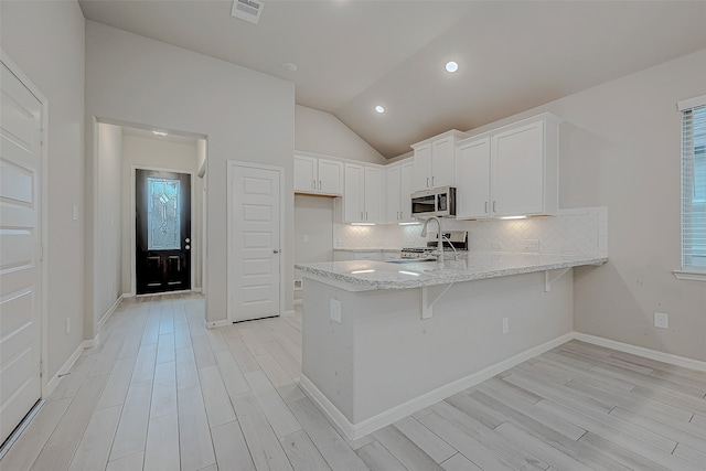 kitchen with lofted ceiling, a healthy amount of sunlight, white cabinetry, and appliances with stainless steel finishes